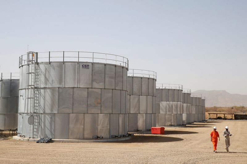 FILE PHOTO: Workers walk past storage tanks at Tullow Oil’s