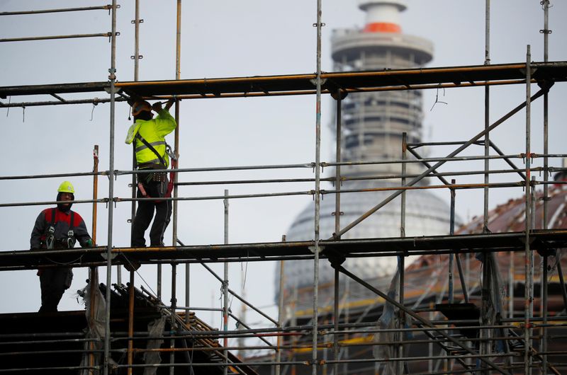 Construction workers dismantle a scaffold in front of television tower