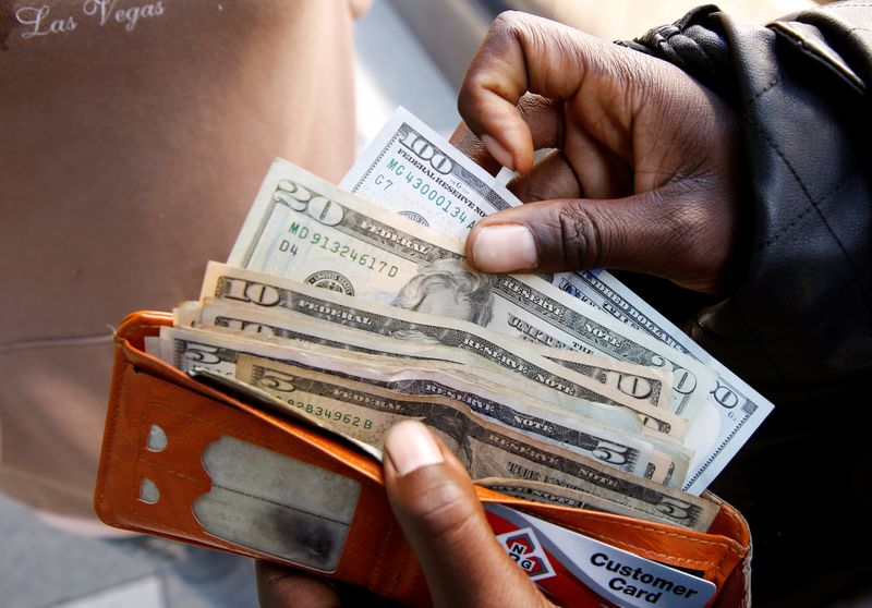 A man displays US dollar notes after withdrawing cash from