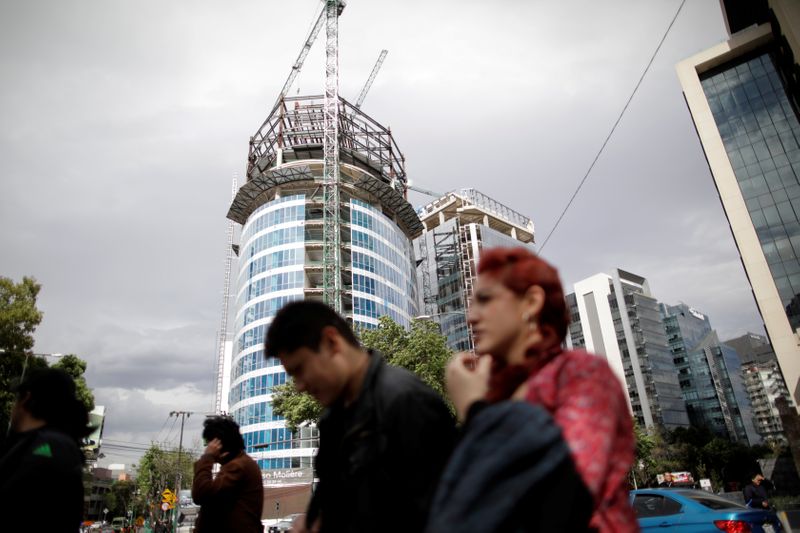 People walk past a building undergoing construction in Mexico City