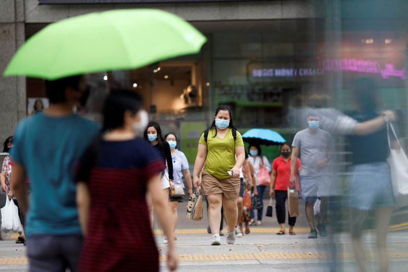 People wearing protective face masks cross a street in Singapore