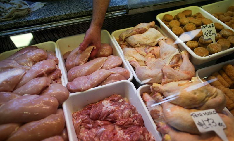 A vendor places chiken breasts for sale in a poultry
