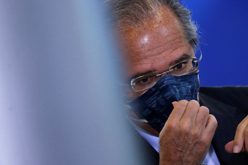 Brazil’s Economy Minister Paulo Guedes adjusts his protective face mask