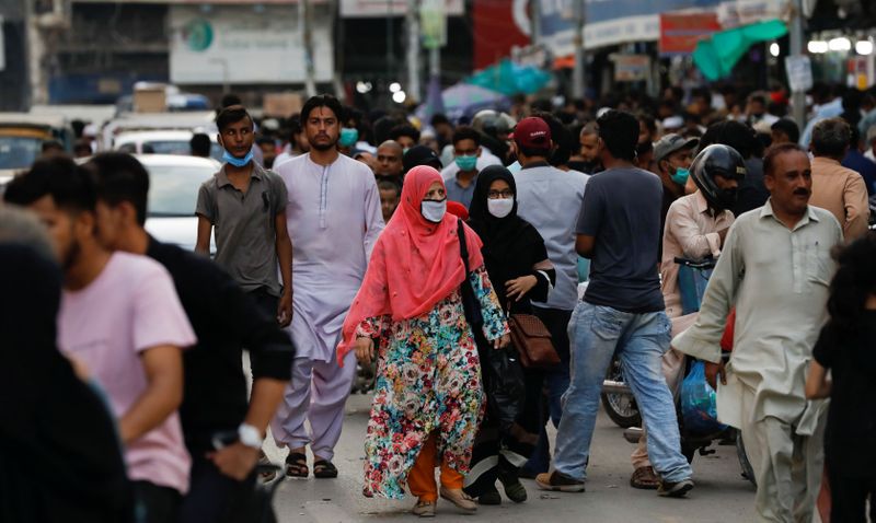 Women wearing protective face masks walk amid the rush of