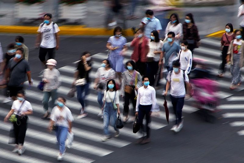 People wearing face masks walk on a street in Shanghai