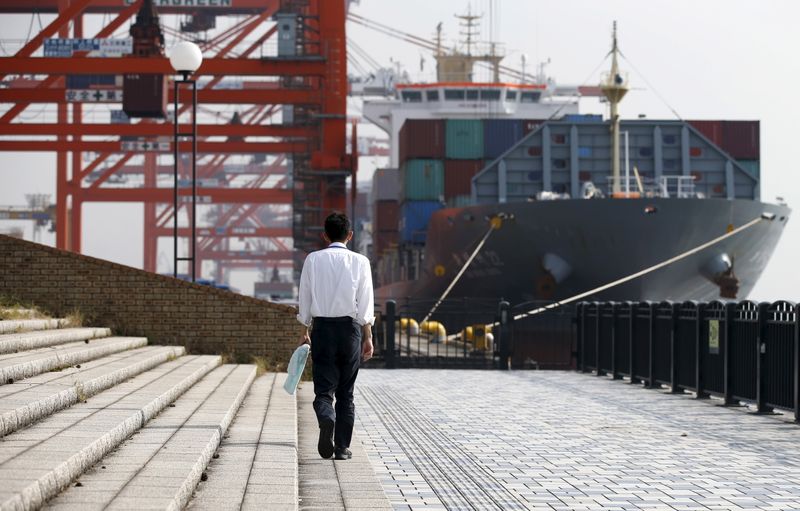 A man walks near a container ship at a port
