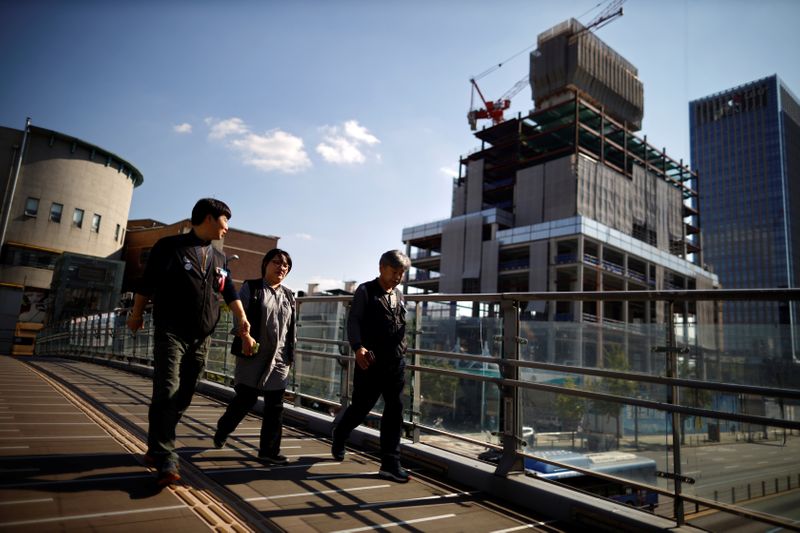 FILE PHOTO: Workers walk past a construction site in Seoul
