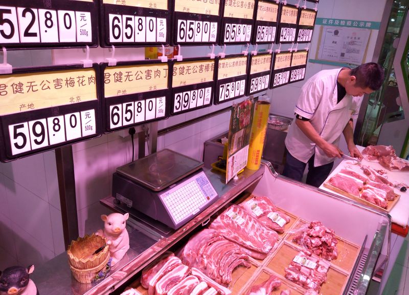 FILE PHOTO: An employee works next to signs showing pork