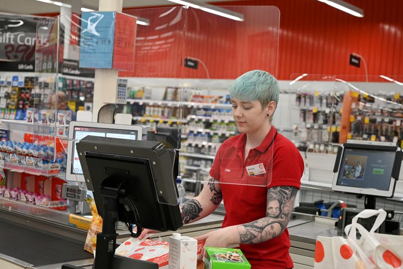 FILE PHOTO: A cashier works behind a protective plexiglass shield