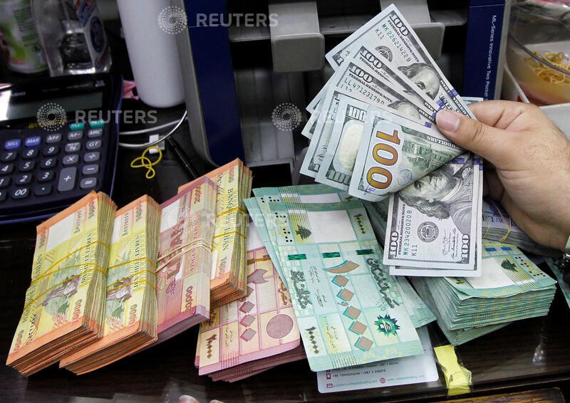 A man counts U.S. dollar banknotes next to Lebanese pounds