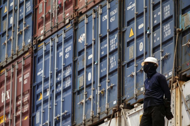 FILE PHOTO: A worker stands next to shipping containers on