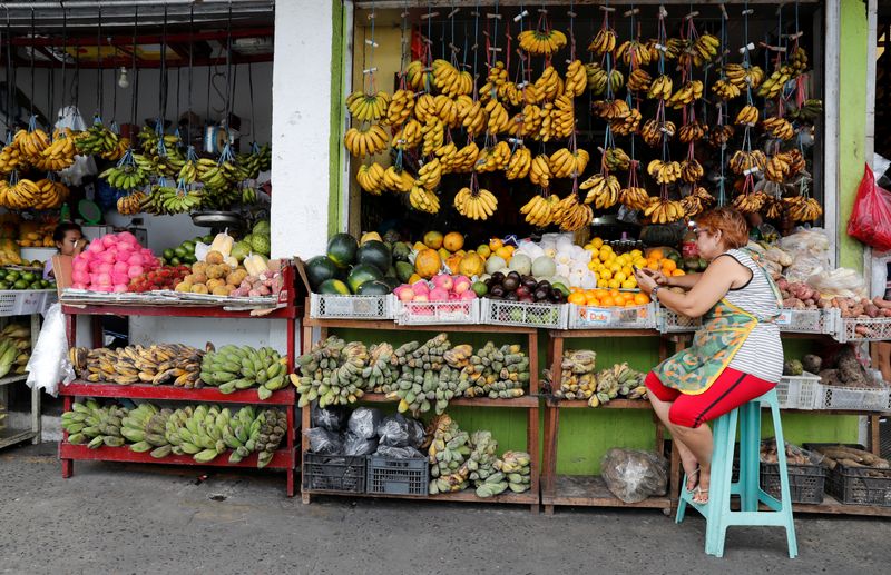 A vendor surfs internet on her mobile phone as she