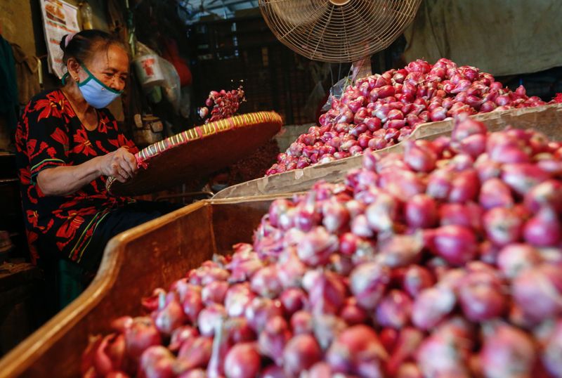 A worker wearing a protective face mask sorts onion at