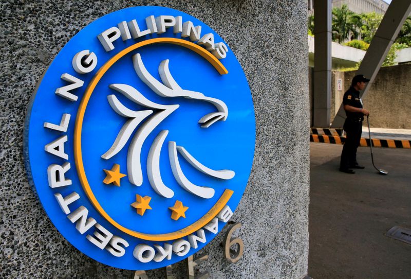 Security guard stands beside a logo of the Bangko Sentral