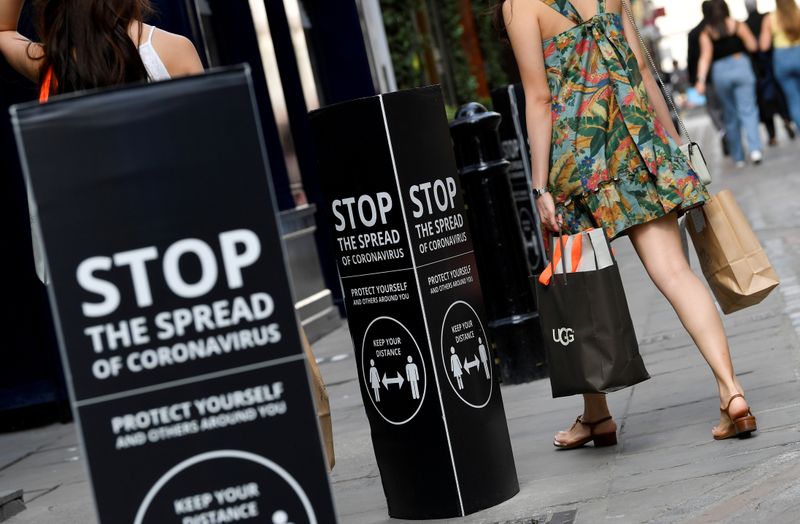FILE PHOTO: Shoppers walk past social distancing signs at the