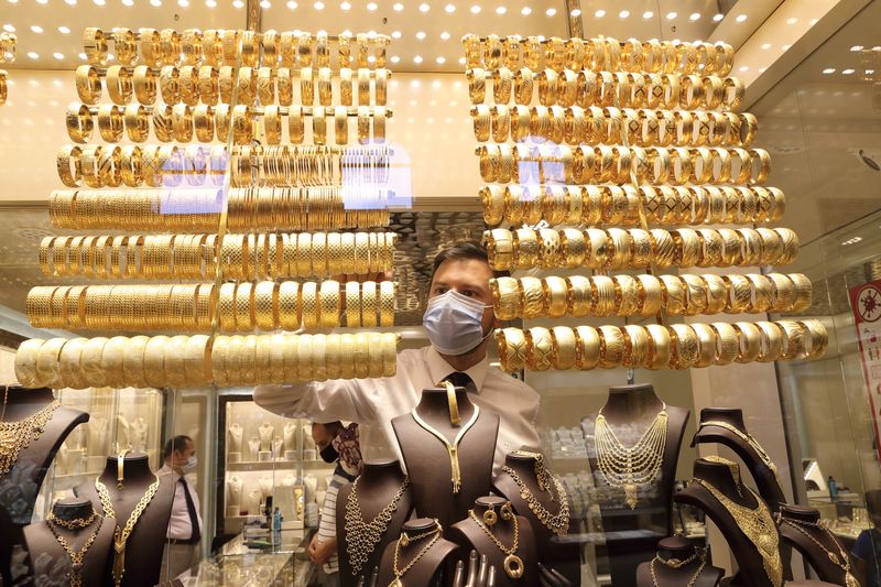 A goldsmith arranges golden bangles at a jewellery shop, in