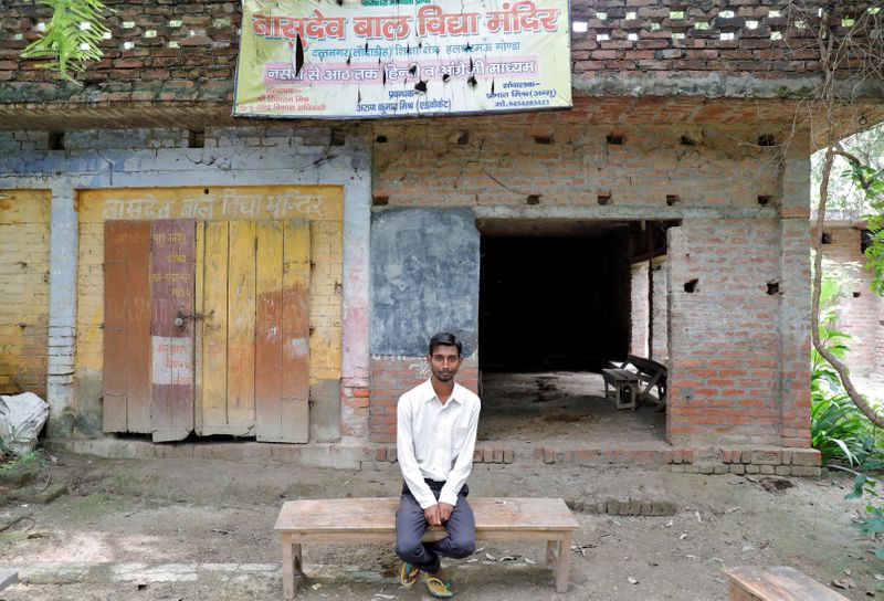 Ashish Kumar poses outside a primary school where he studied