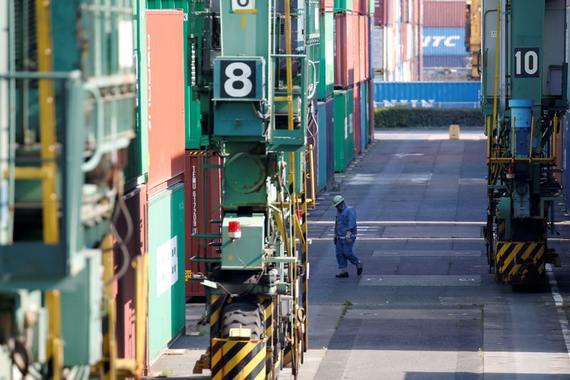 FILE PHOTO: A worker walks between shipping containers at a