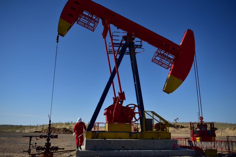 Worker inspects a pump jack at an oil field in