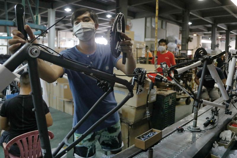 Workers build bikes at a factory that belongs to Acetrikes