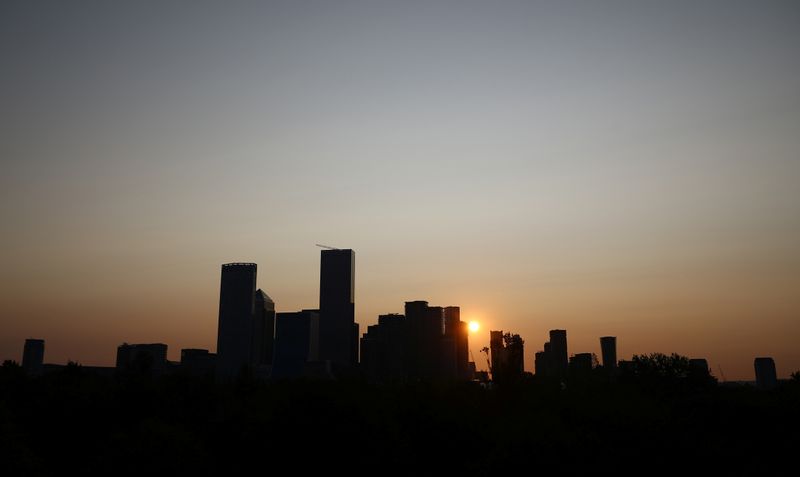 The sun rises behind Canary Wharf financial district in London