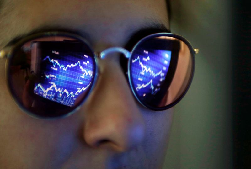 A computer screen showing stock graphs is reflected on glasses