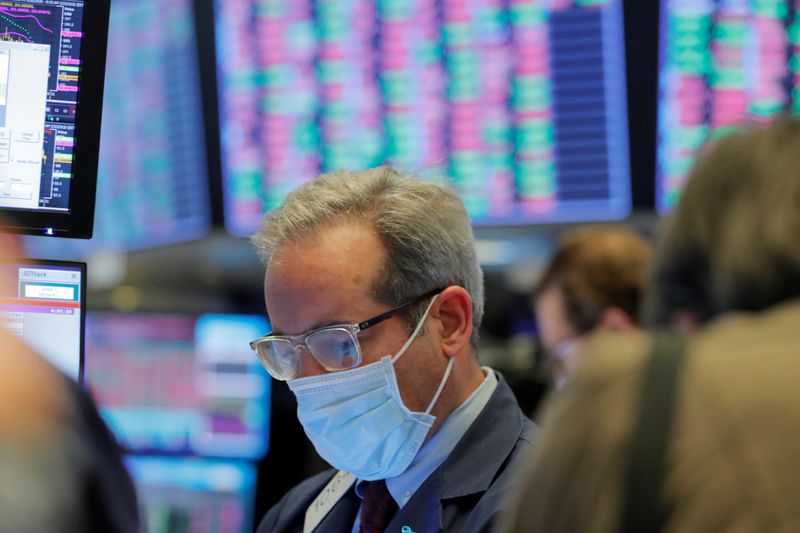 A trader wears a mask as he works on the