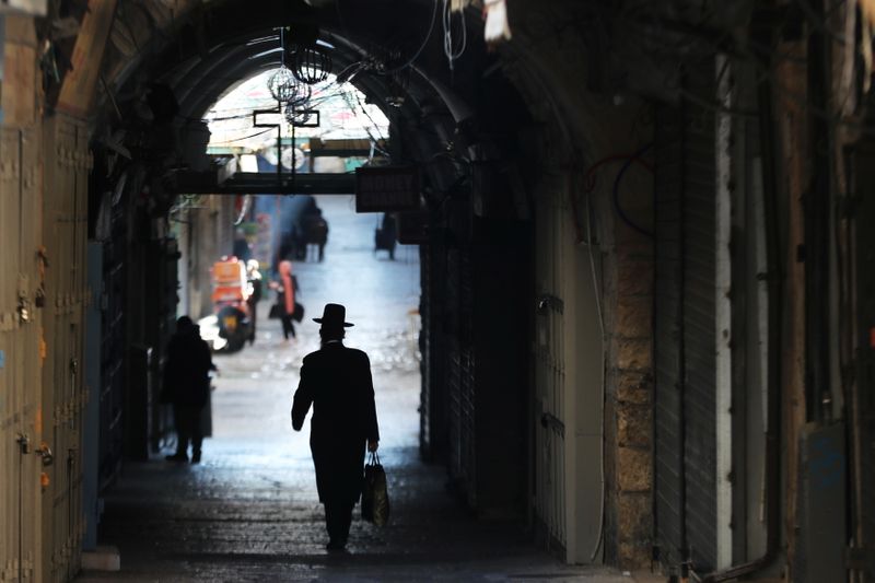 An ultra-Orthodox Jewish man walks past a shuttered shop during