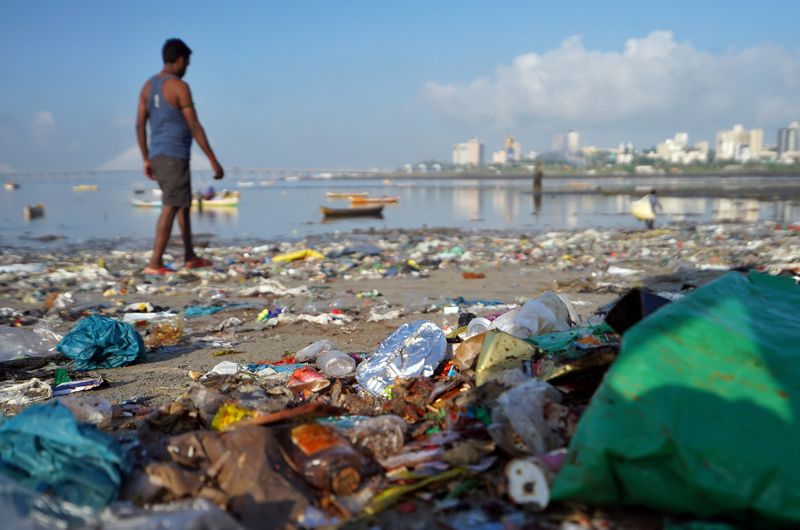 FILE PHOTO: A man walks on a garbage-strewn beach in