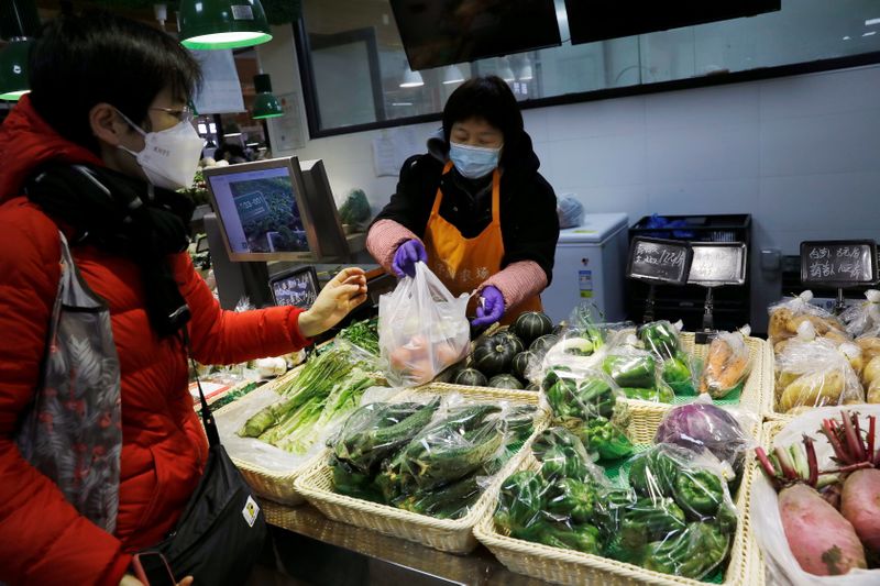 People wearing face masks shop at a market, following new