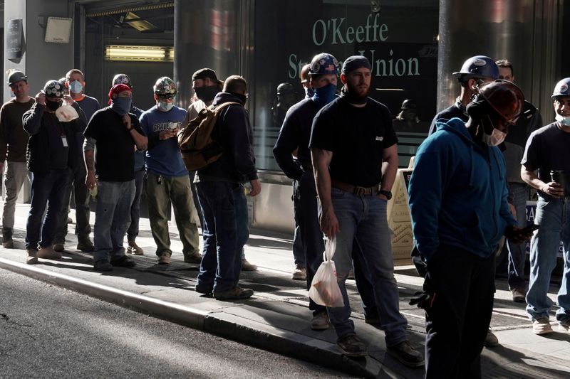 FILE PHOTO: Construction workers wait in line to do a