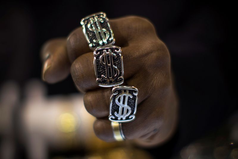 A man wears dollar sign rings in a jewellery shop