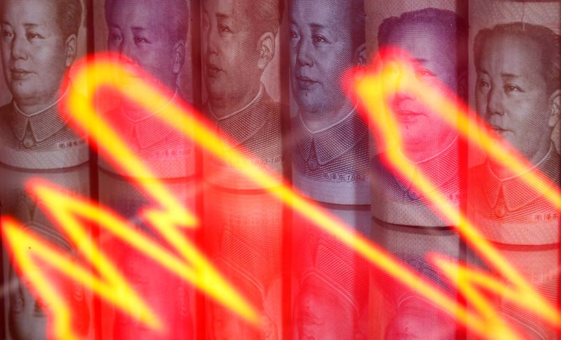 FILE PHOTO: Chinese Yuan banknotes are seen behind illuminated stock