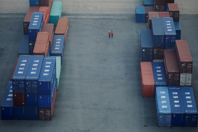 Workers walk past shipping containers at Pyeongtaek port in Pyeongtaek