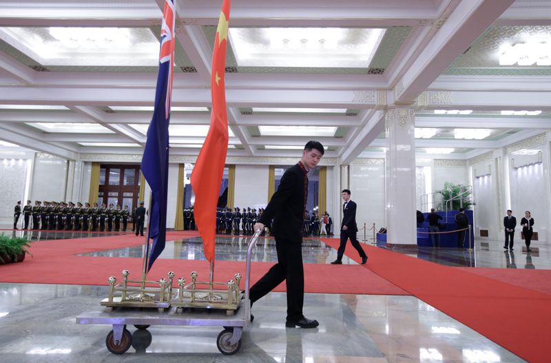 An attendant moves flags of New Zealand and China after