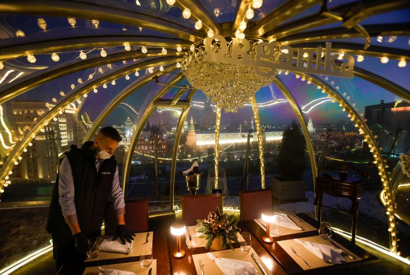 FILE PHOTO: A waiter sets a table inside a transparent