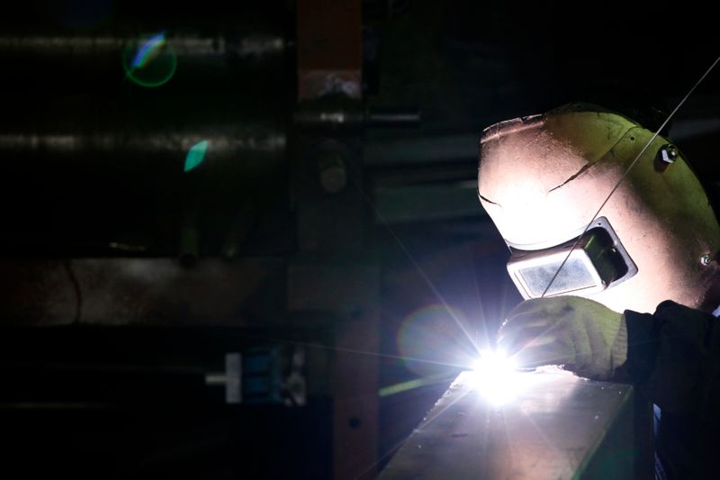 A worker welds iron at his steel product shop in