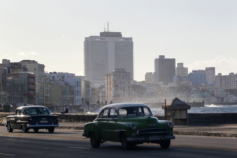 Vintage cars drive on the seafront boulevard El Malecon in