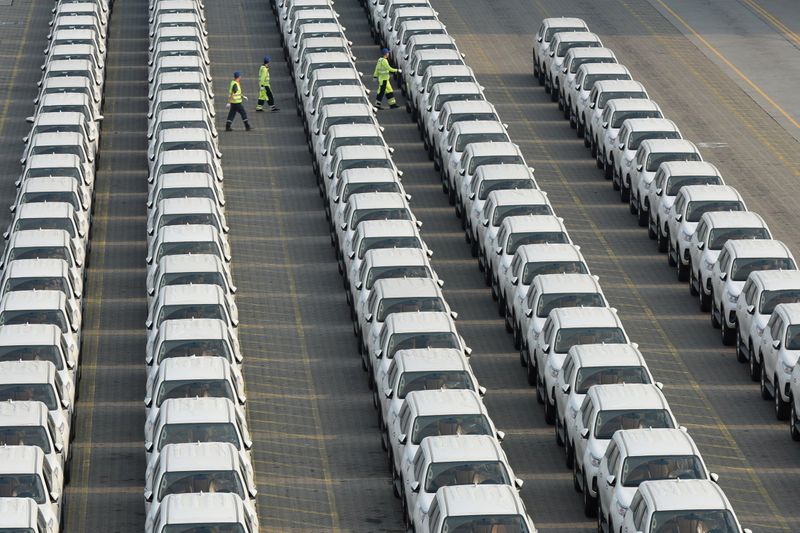 Workers walk among the newly arrived imported Toyota cars at
