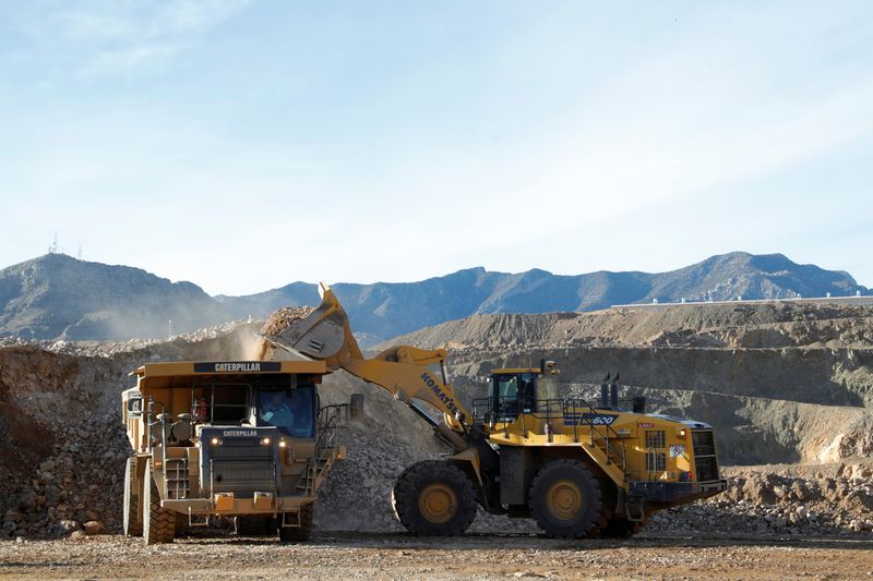 A wheel loader operator fills a truck with ore at