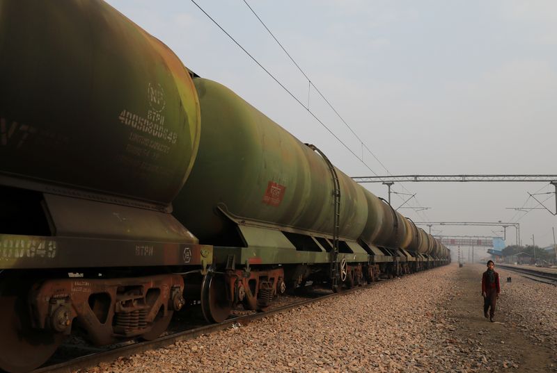 A boy walks past an oil tanker train stationed at