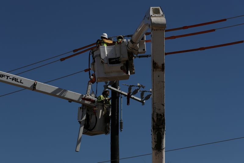 Workers install a utility pole to support power lines after