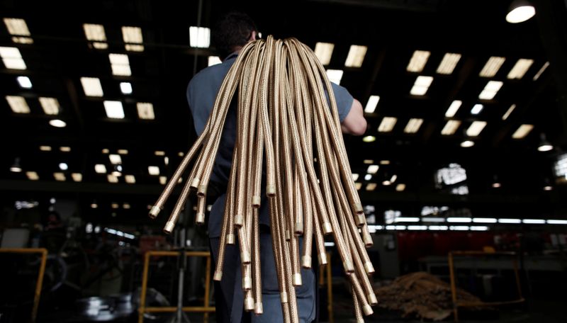 An employee carries copper hoses at the SPTF metallurgical company