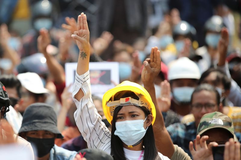 A woman shows a three-finger salute during a protest against