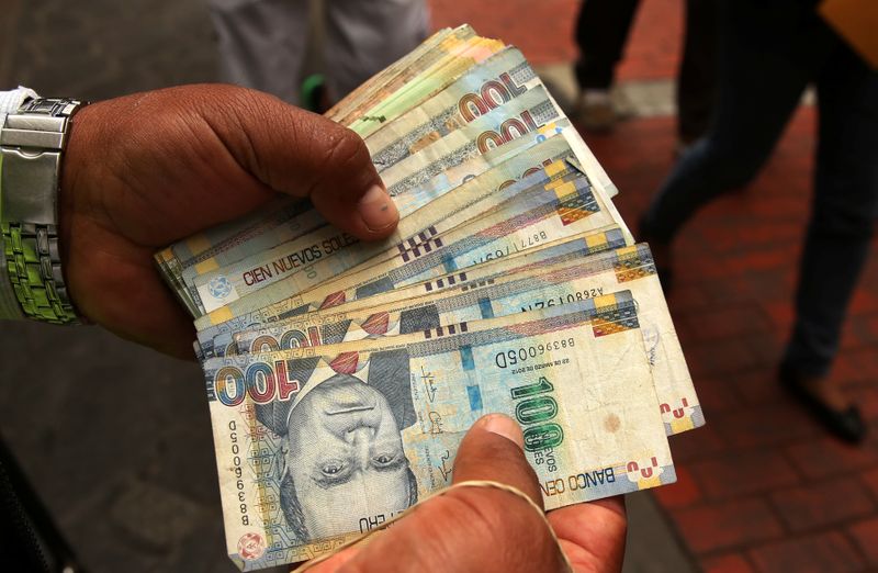 A money changer holds Peruvian Sol bills at a street
