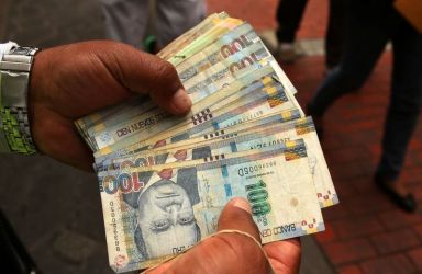 A money changer holds Peruvian Sol bills at a street