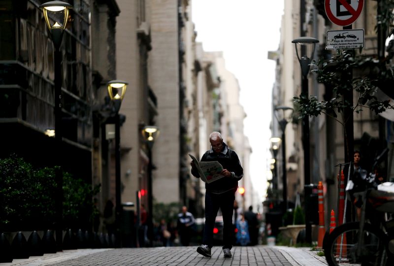 FILE PHOTO: A man reads a newspaper as he walks