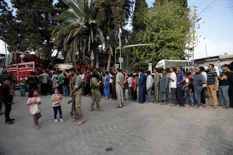 FILE PHOTO: People stand in a queue to get bread