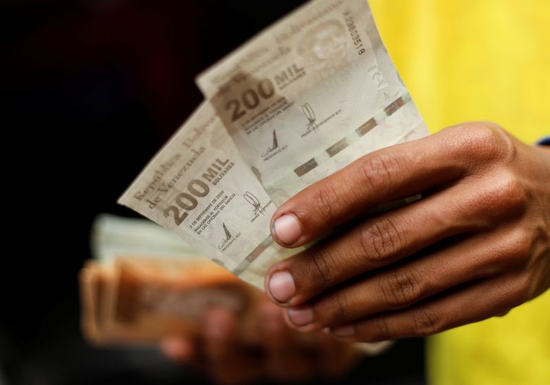 The assistant of a bus driver holds banknotes of 200,000