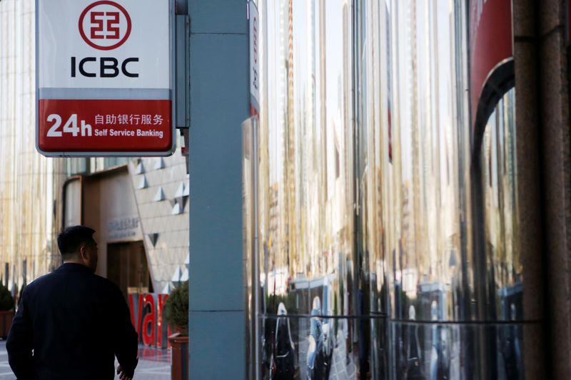 Man walks past a branch of Industrial and Commercial Bank